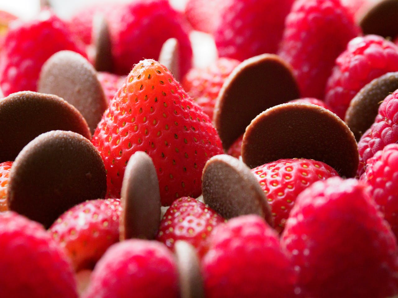 menu-07 Fresh strawberries, raspberries, and dark chocolate chips in a close-up view, perfect for dessert lovers.